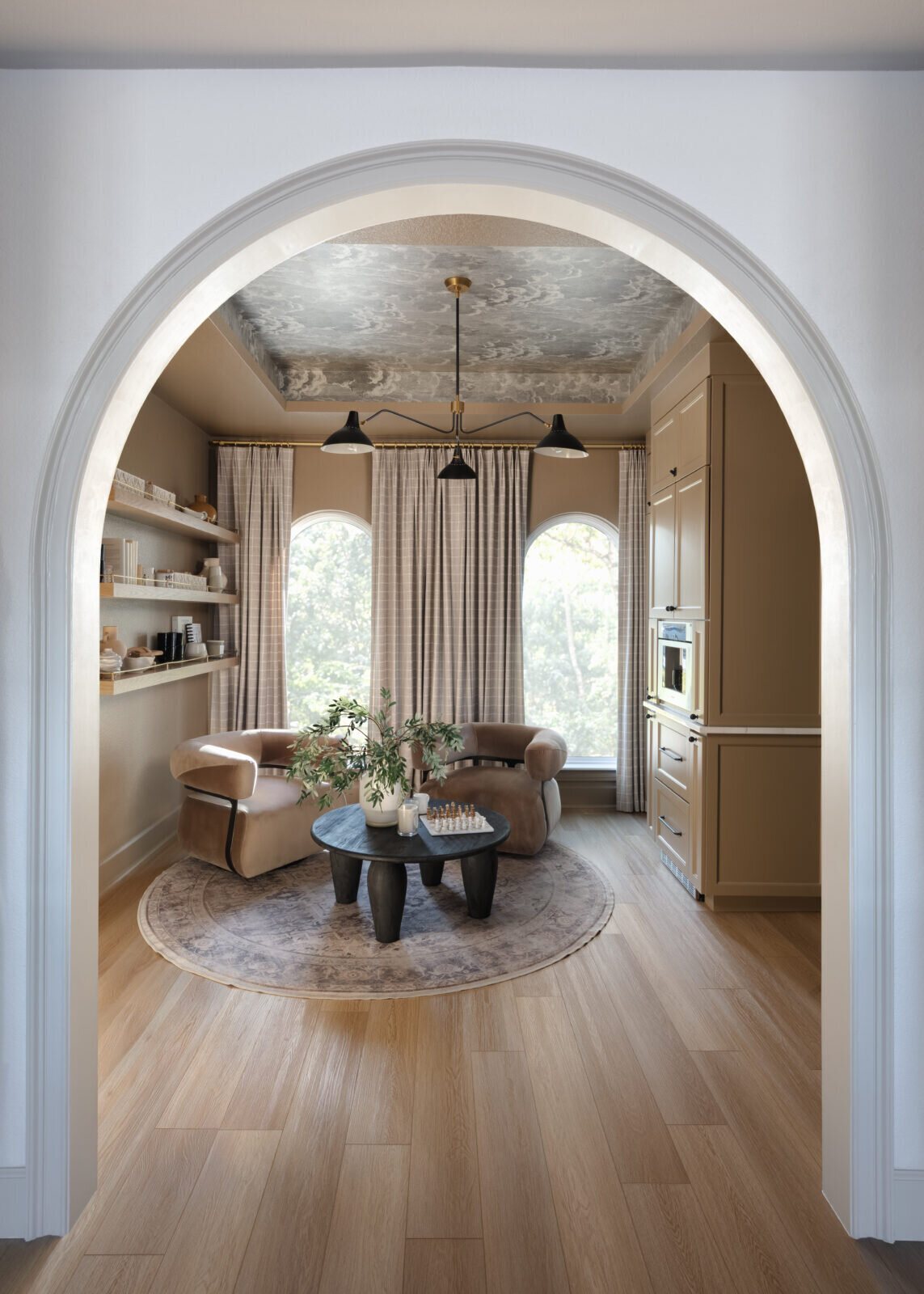Arched opening into a sitting room with a marbled ceiling treatment and a round table in the Alexandria project by Jennifer Kizzee Design