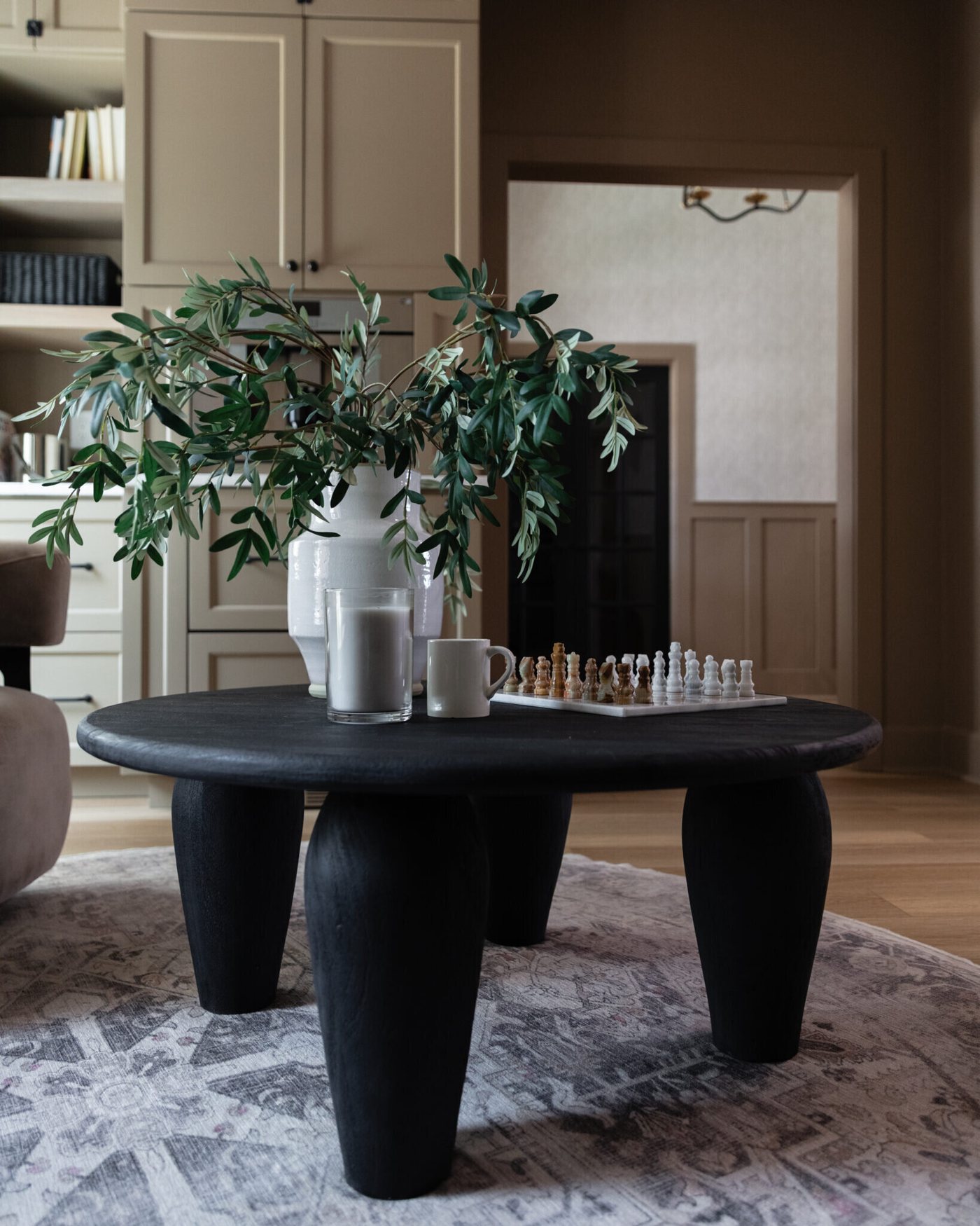 Black sculptural coffee table on a patterned rug in a living room in the Alexandria project by Jennifer Kizzee Design