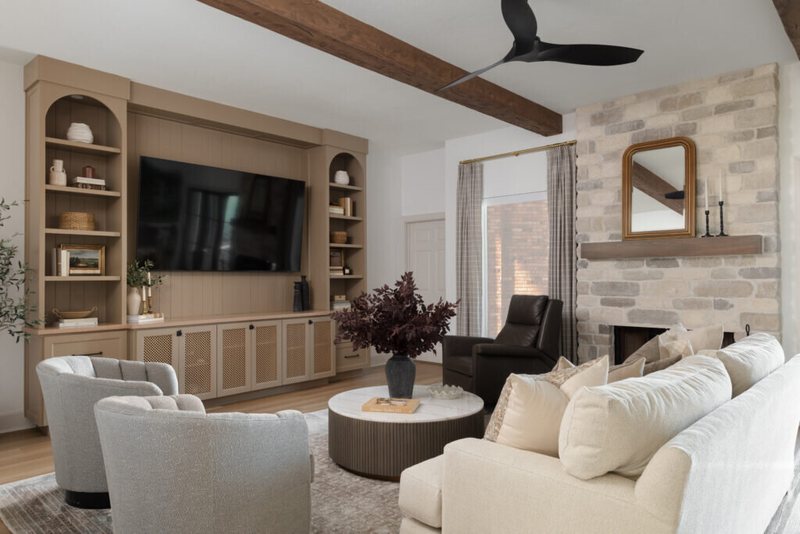 Living room with a stone fireplace, exposed beams and white built-in cabinetry in the Alexandria project by Jennifer Kizzee Design