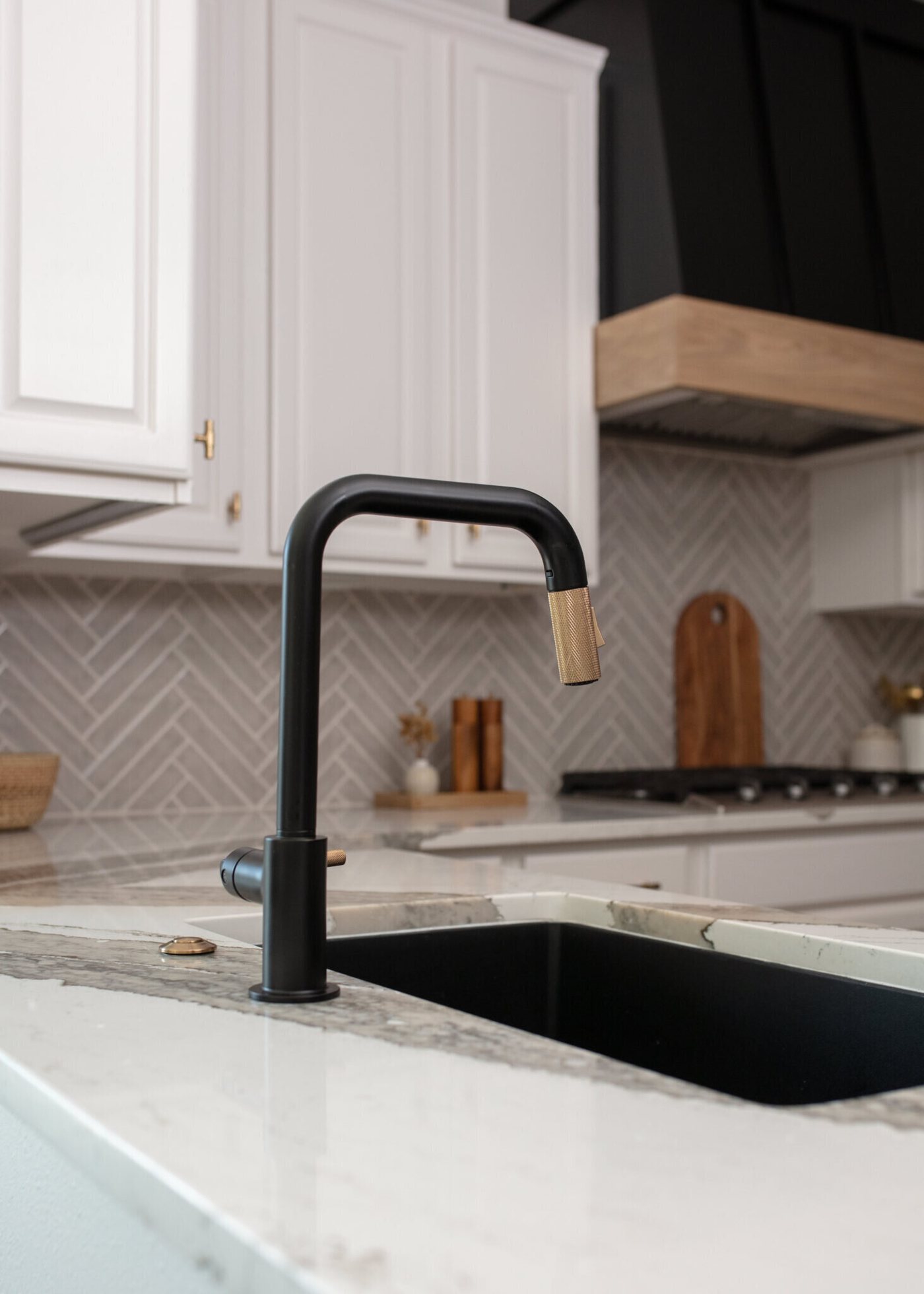 Black gooseneck faucet over a black undermount sink in veined quartz in the Ambrose Kitchen project by Jennifer Kizzee Design