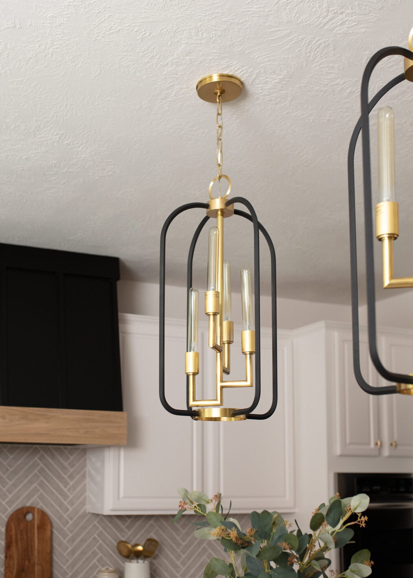 Brass and black lantern pendant hung over the island in the Ambrose Kitchen project by Jennifer Kizzee Design