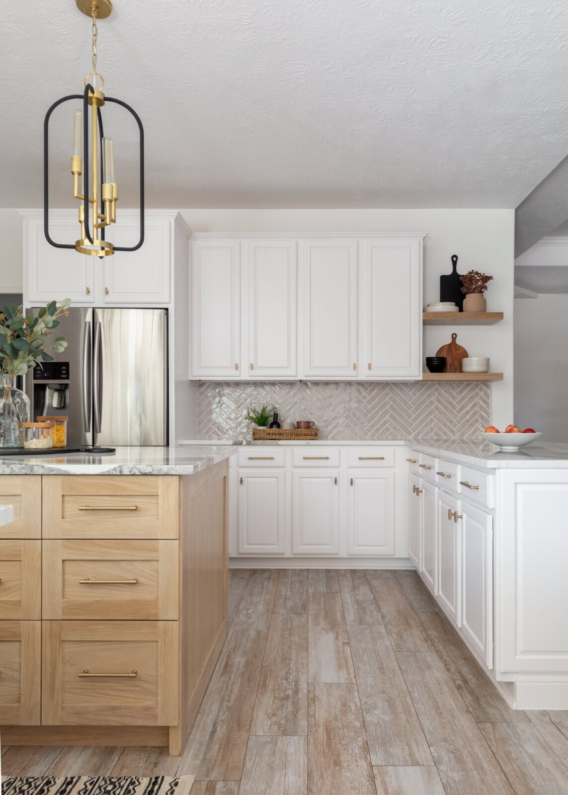 White perimeter cabinetry with brass hardware beside a white oak island in the Ambrose Kitchen project by Jennifer Kizzee Design