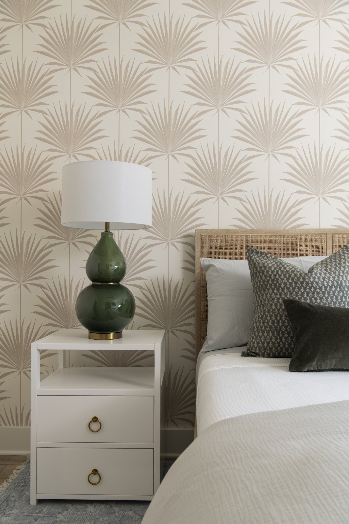 Green gourd lamp and olive pillows against palm print wallpaper in the bedroom in the Bolivar Beach House project by Jennifer Kizzee Design