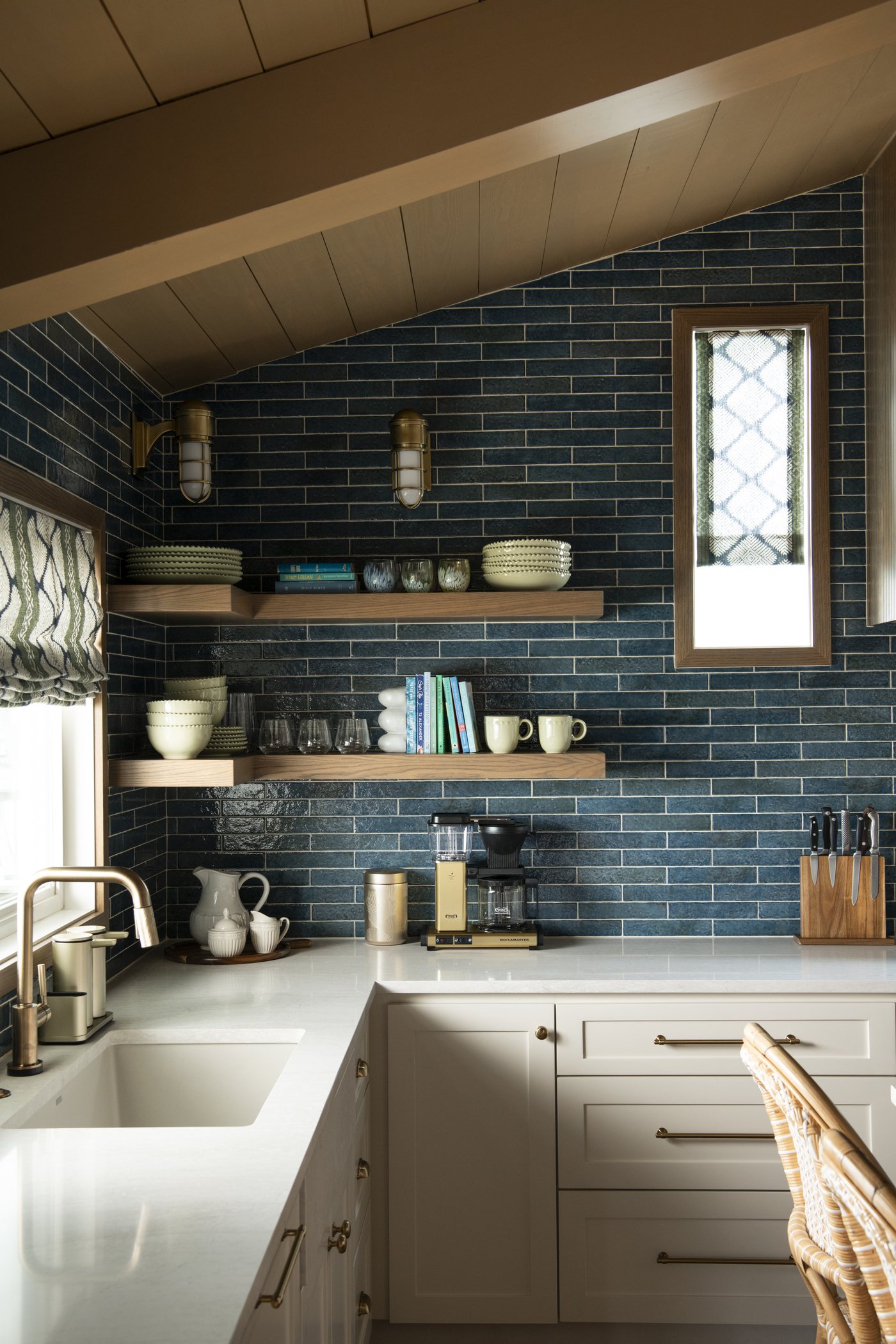 Kitchen corner with open wood shelves, blue green tile and a leaded glass window in the Bolivar Beach House project by Jennifer Kizzee Design