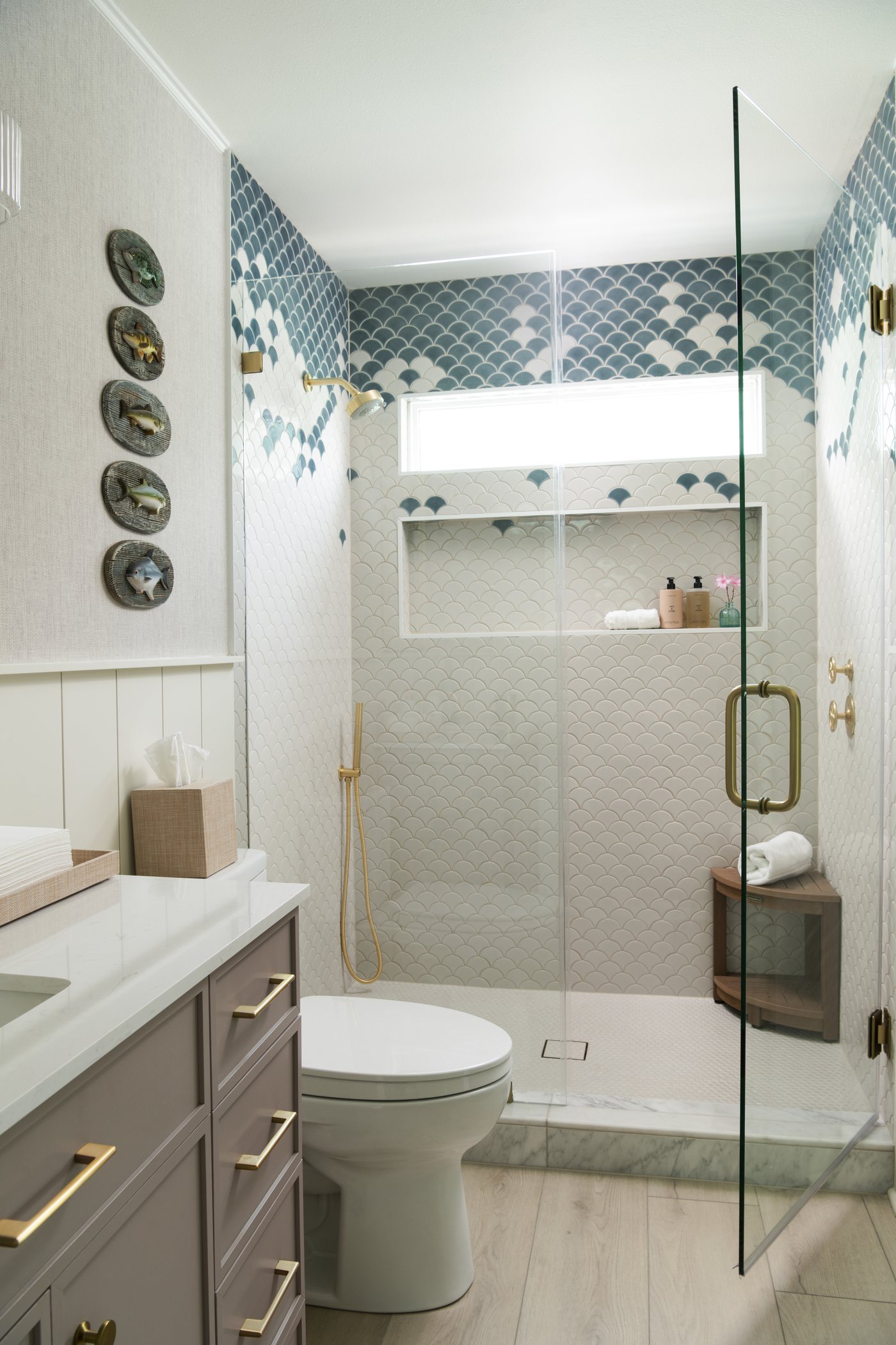 Second bath with a blue tiled shower niche, a white vanity and decorative plates in the Bolivar Beach House project by Jennifer Kizzee Design