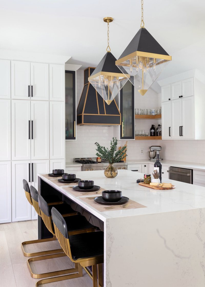 Quartz island with black and brass counter stools under faceted pendants in the Branstetter Kitchen project by Jennifer Kizzee Design