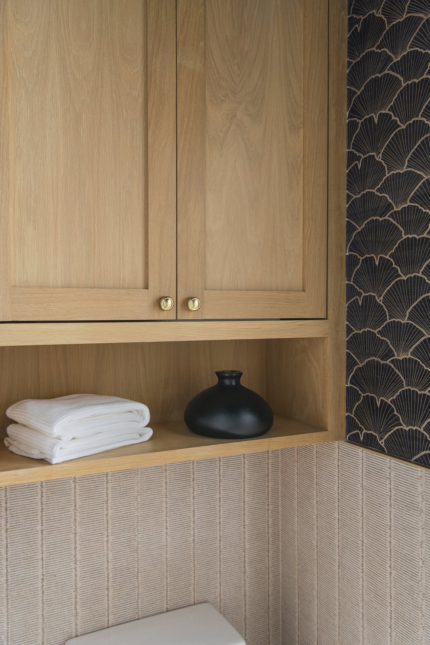 Oak cabinetry meeting the scalloped tile wall above a bath in the Collective Washroom project by Jennifer Kizzee Design