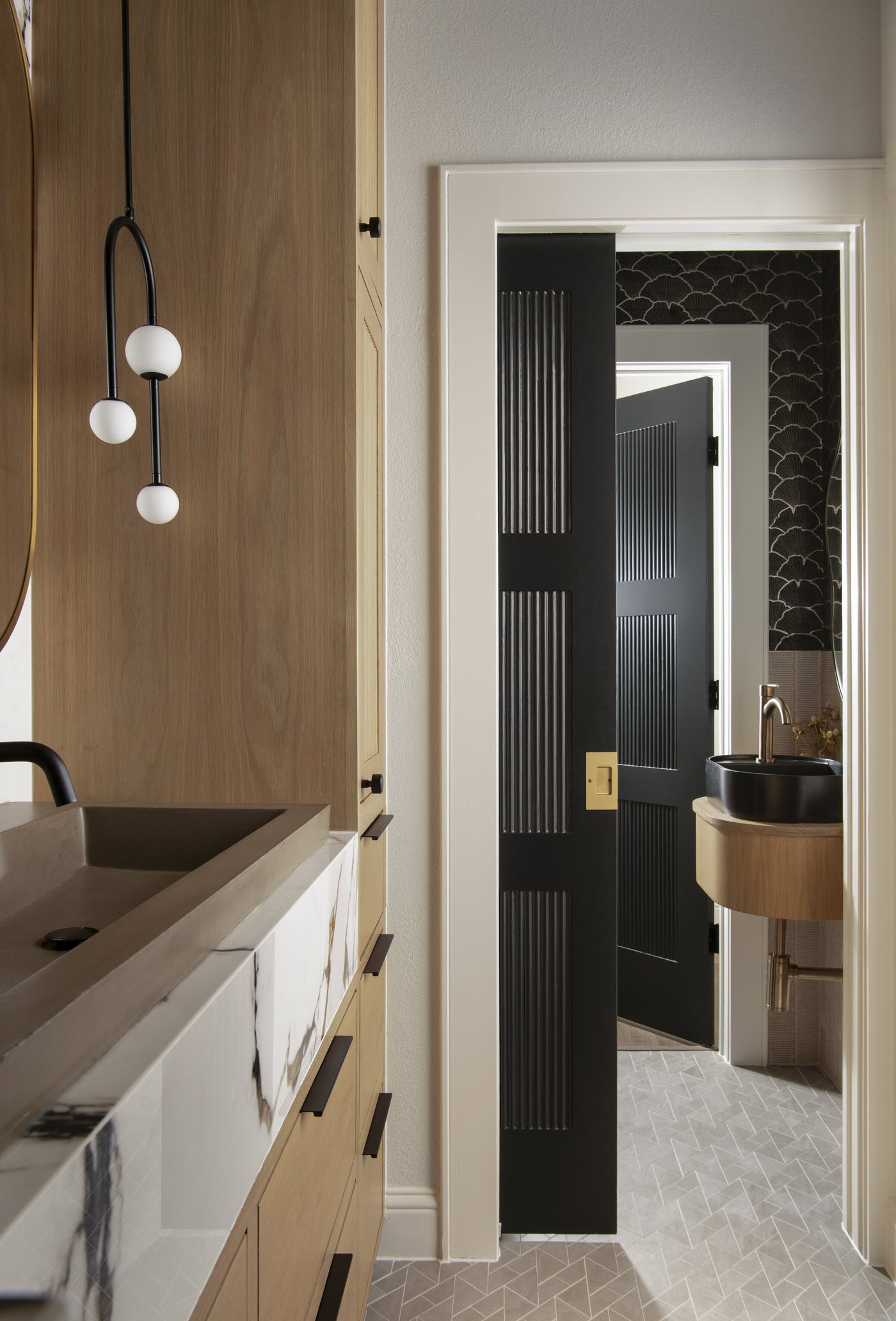 Pendant light beside the vanity with the fluted door open to the hall in the Collective Washroom project by Jennifer Kizzee Design
