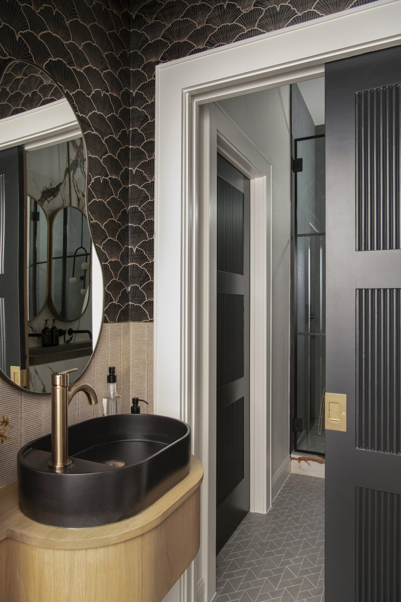 Powder room seen from the doorway with the vessel sink and shower beyond in the Collective Washroom project by Jennifer Kizzee Design