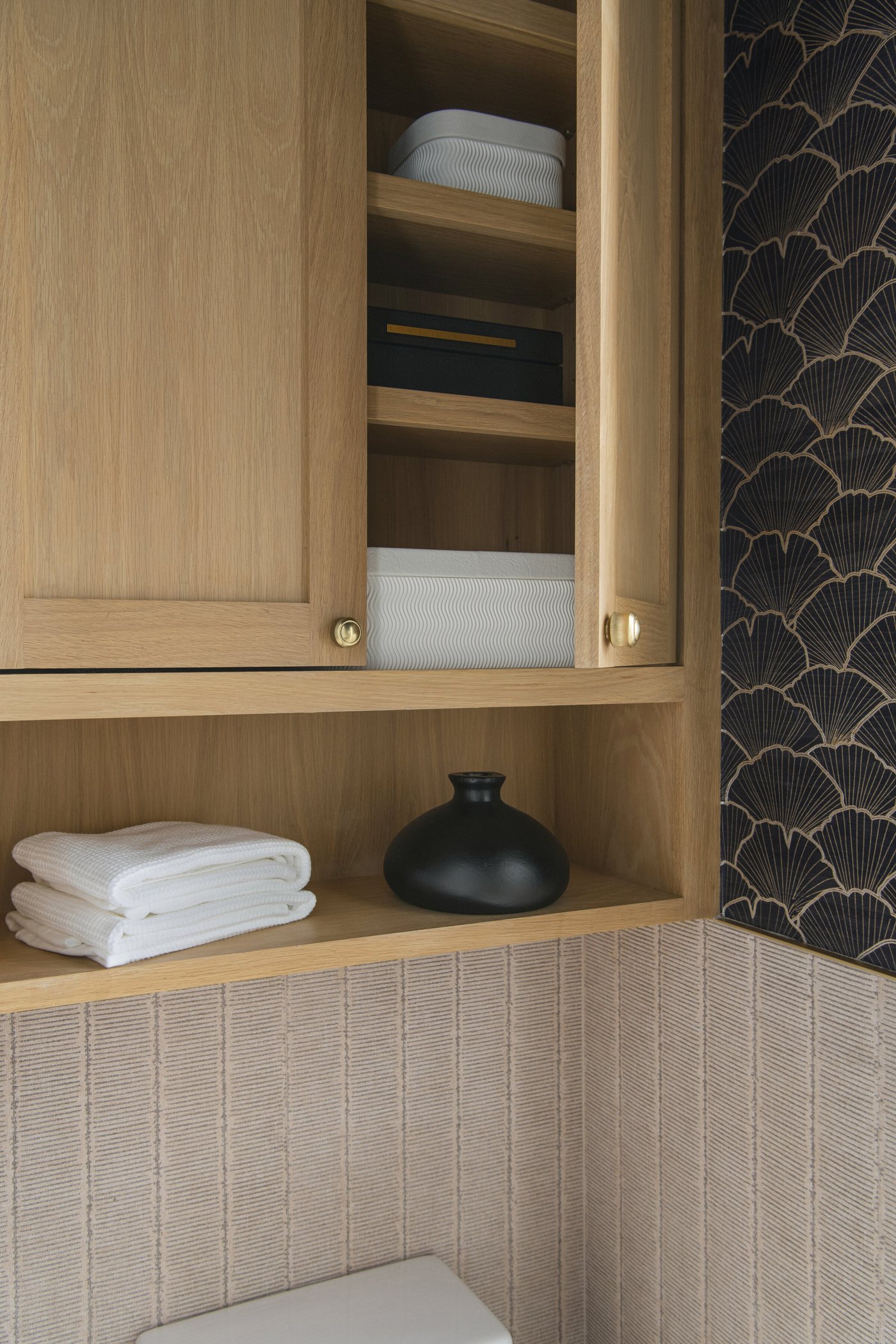 White oak shelf and cabinet against scalloped tile holding folded towels in the Collective Washroom project by Jennifer Kizzee Design