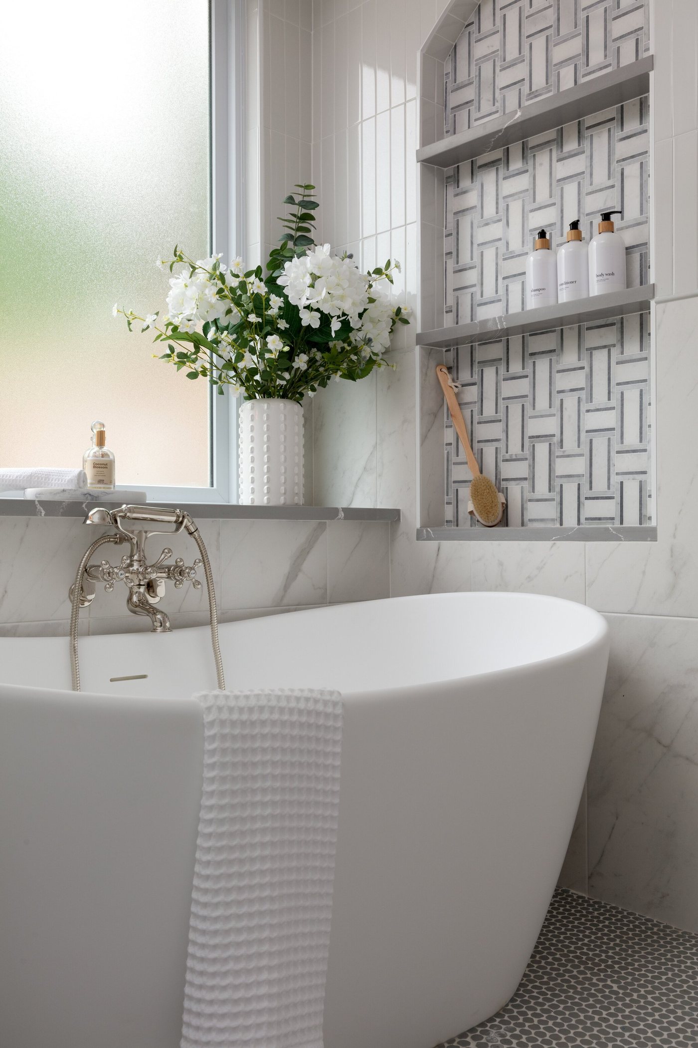 Freestanding tub under a window beside an arched tile niche in the Crescent Bath project by Jennifer Kizzee Design