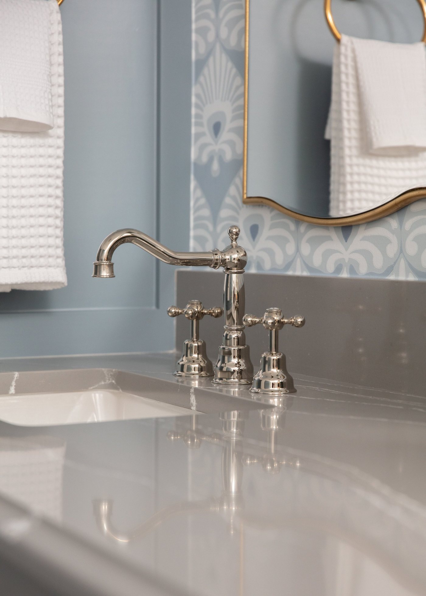 Polished nickel faucet on a marble counter under a gilt arched mirror in the Crescent Bath project by Jennifer Kizzee Design