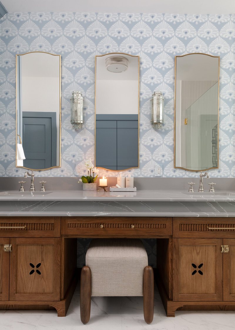 Walnut double vanity with marble counters under arched mirrors and glass sconces in the Crescent Bath project by Jennifer Kizzee Design