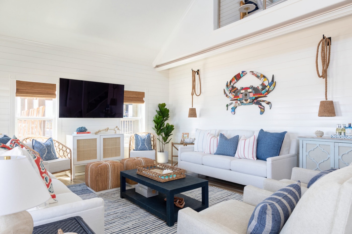 Great room under a cathedral ceiling with white shiplap walls and a multicolor crab sculpture above the sofa in the Crystal Beach Vacation Home project by Jennifer Kizzee Design