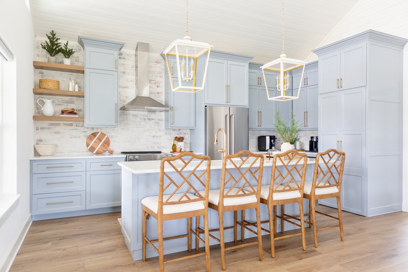 Kitchen with powder blue cabinetry, white and brass lantern pendants, and rattan fretwork counter stools in the Emma Lane Guest House project by Jennifer Kizzee Design