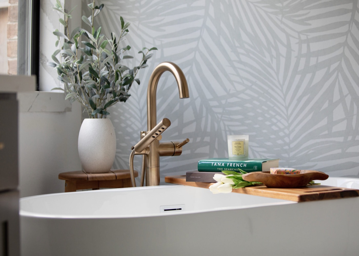 Brushed gold floor-mount tub filler beside a wood bath caddy and olive branches in the Evergreen Suite Bathroom project by Jennifer Kizzee Design