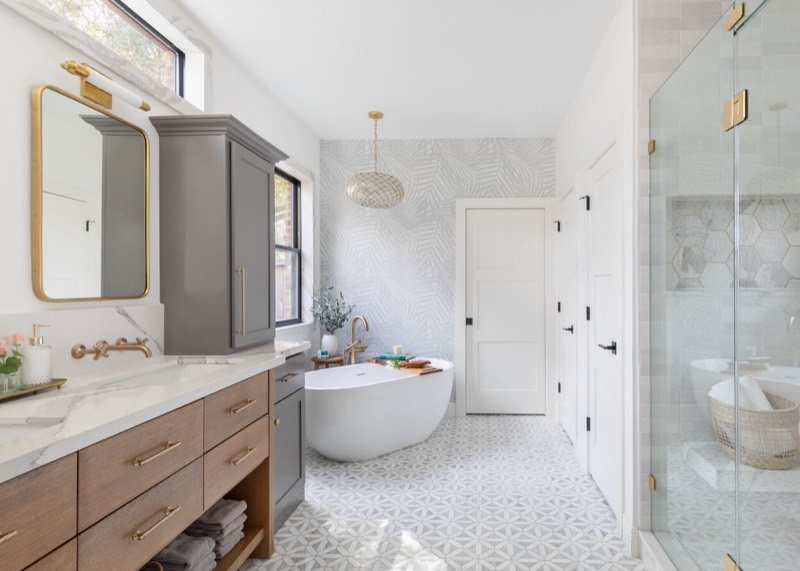 Freestanding tub against sage palm wallpaper with a capiz pendant and a two-tone double vanity in the Evergreen Suite Bathroom project by Jennifer Kizzee Design