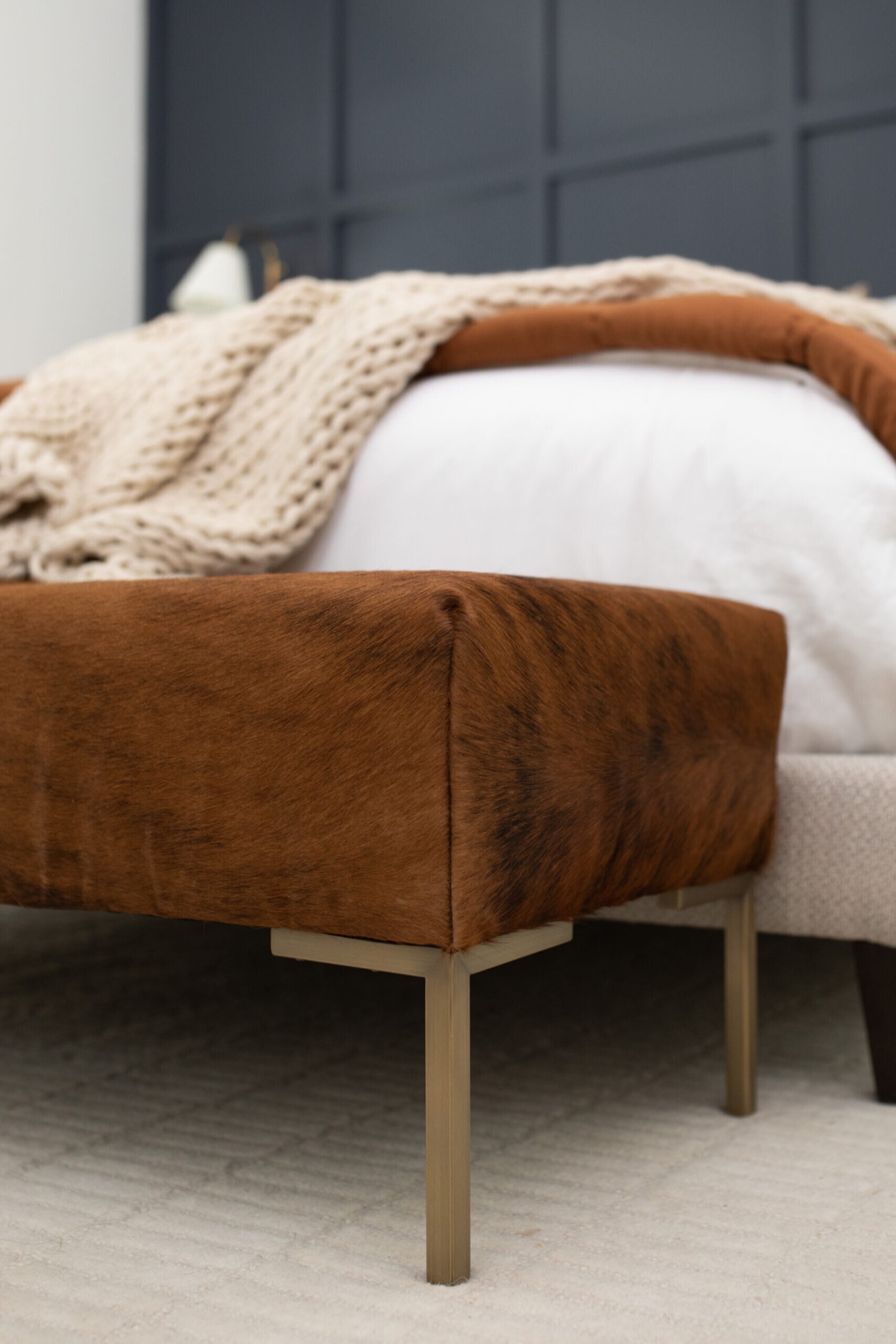 Brindle cowhide bench on brass legs at the foot of the bed in the Evergreen Suite Bedroom project by Jennifer Kizzee Design