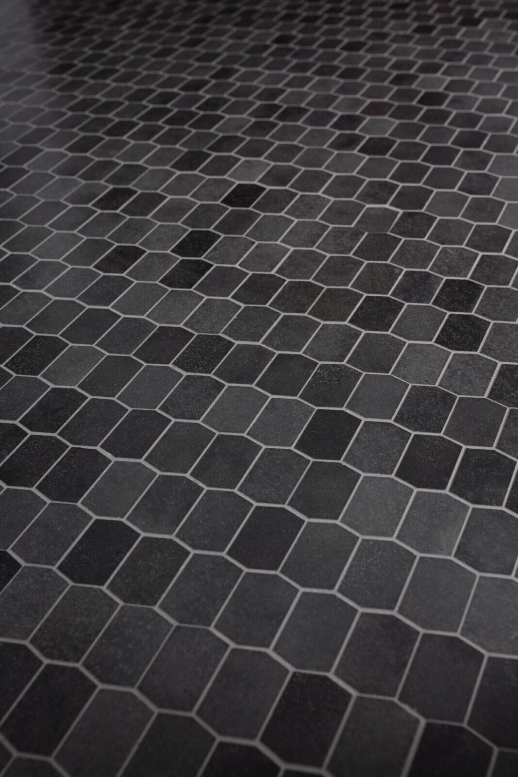 Black hex mosaic floor tile laid wall to wall in the Fox Run Modern Bath project by Jennifer Kizzee Design