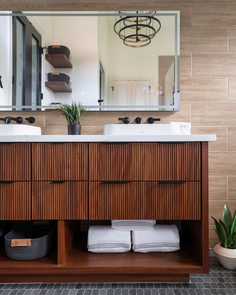 Fluted walnut floating vanity with twin basins and matte black fittings in the Fox Run Modern Bath project by Jennifer Kizzee Design