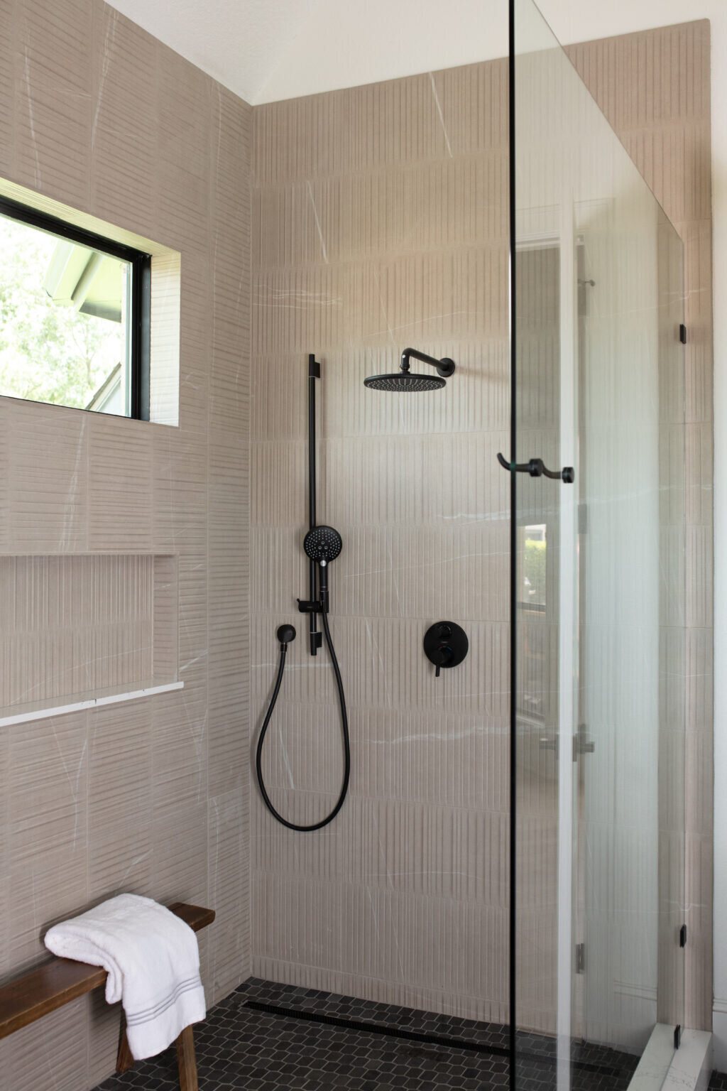 Glass shower enclosure with a black rain head and hand shower in the Fox Run Modern Bath project by Jennifer Kizzee Design