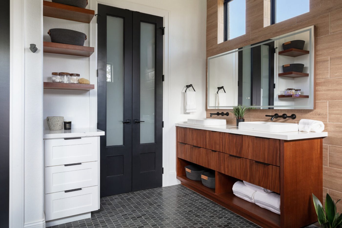 Vanity wall with twin mirrors, open walnut shelves and a black door beyond in the Fox Run Modern Bath project by Jennifer Kizzee Design