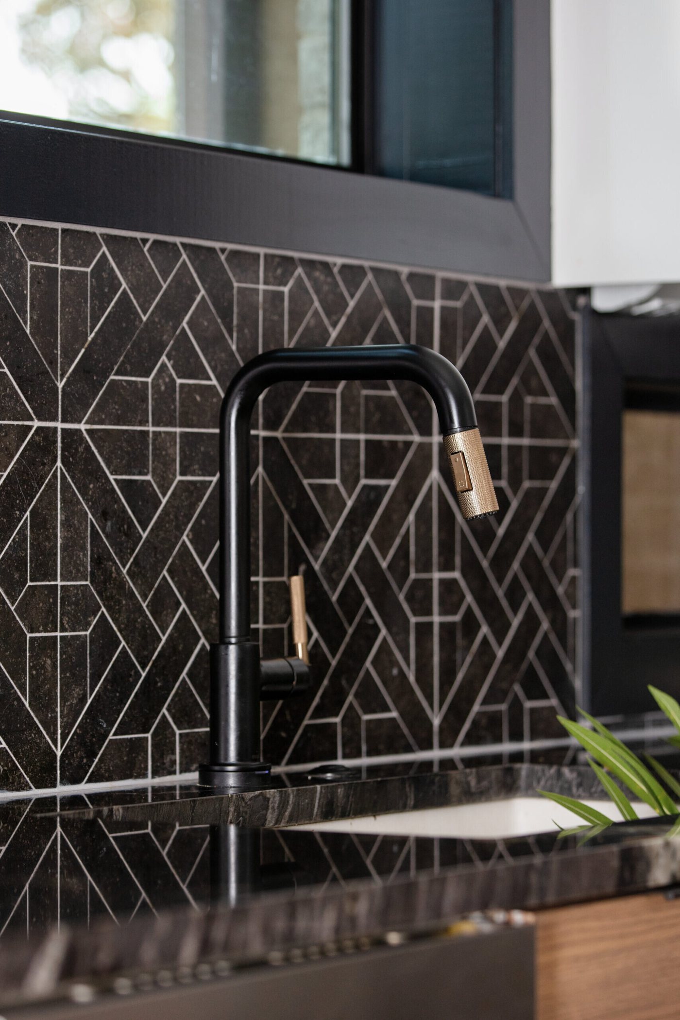 Black gooseneck faucet with a brass handle over an undermount sink in the Fox Run Modern Kitchen project by Jennifer Kizzee Design