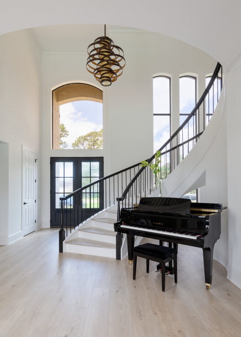 Two story entry with a curved staircase and a grand piano in the Fox Run Modern Kitchen project by Jennifer Kizzee Design