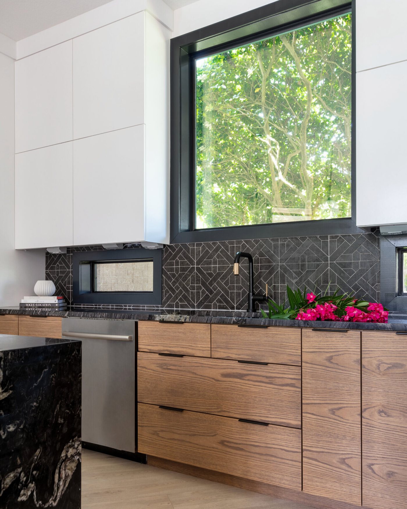 Walnut cabinetry run under a black framed window with black stone counters in the Fox Run Modern Kitchen project by Jennifer Kizzee Design