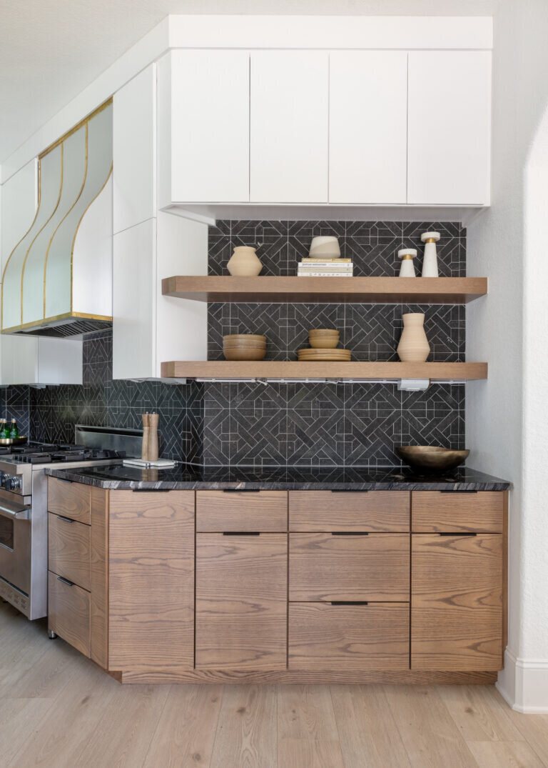 Walnut drawer bank under black stone counters beside open shelves in the Fox Run Modern Kitchen project by Jennifer Kizzee Design