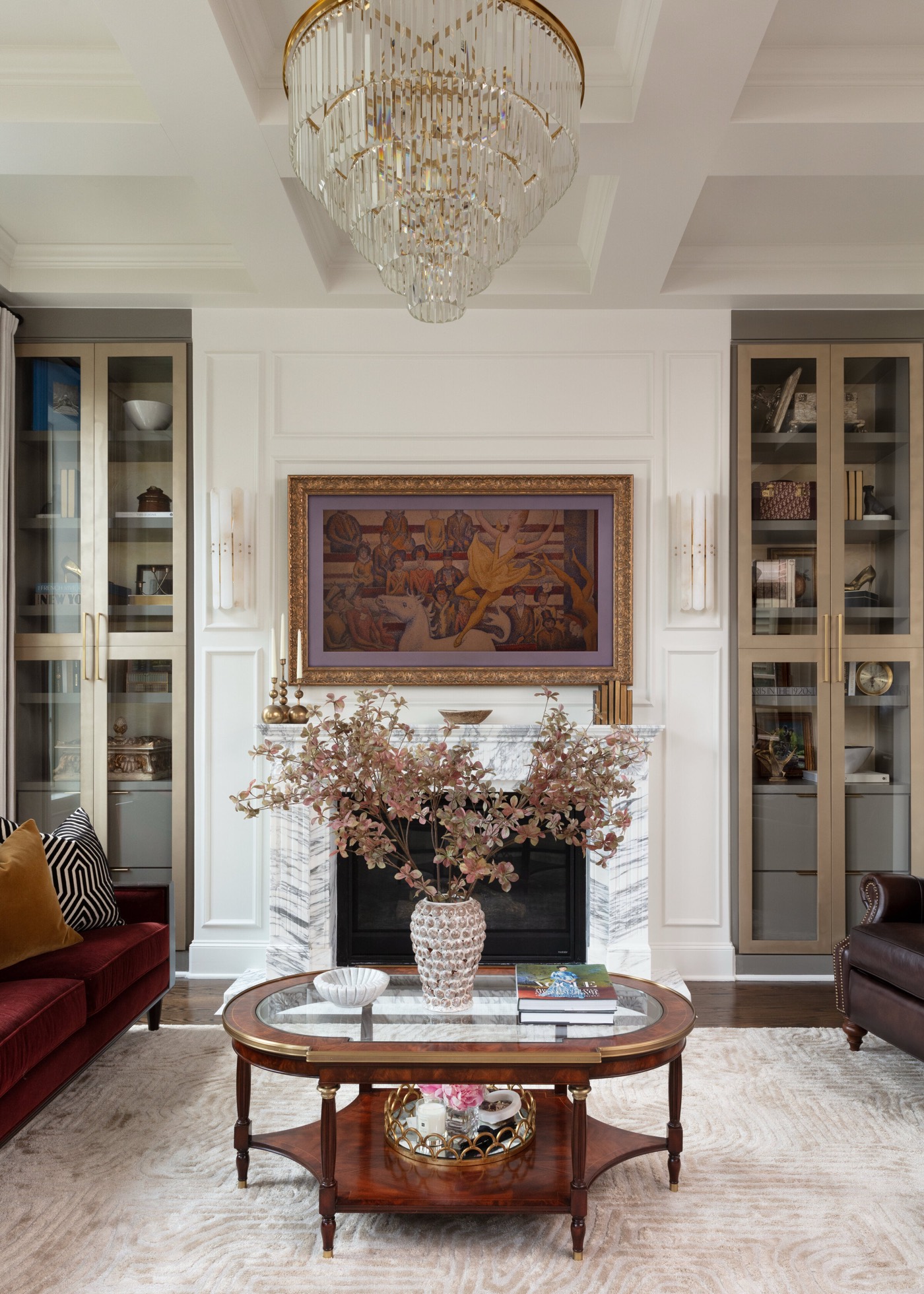 Living room fireplace with a gilt-framed painting hung between tall glass-front built-in cabinets in the Gateway Condo project by Jennifer Kizzee Design
