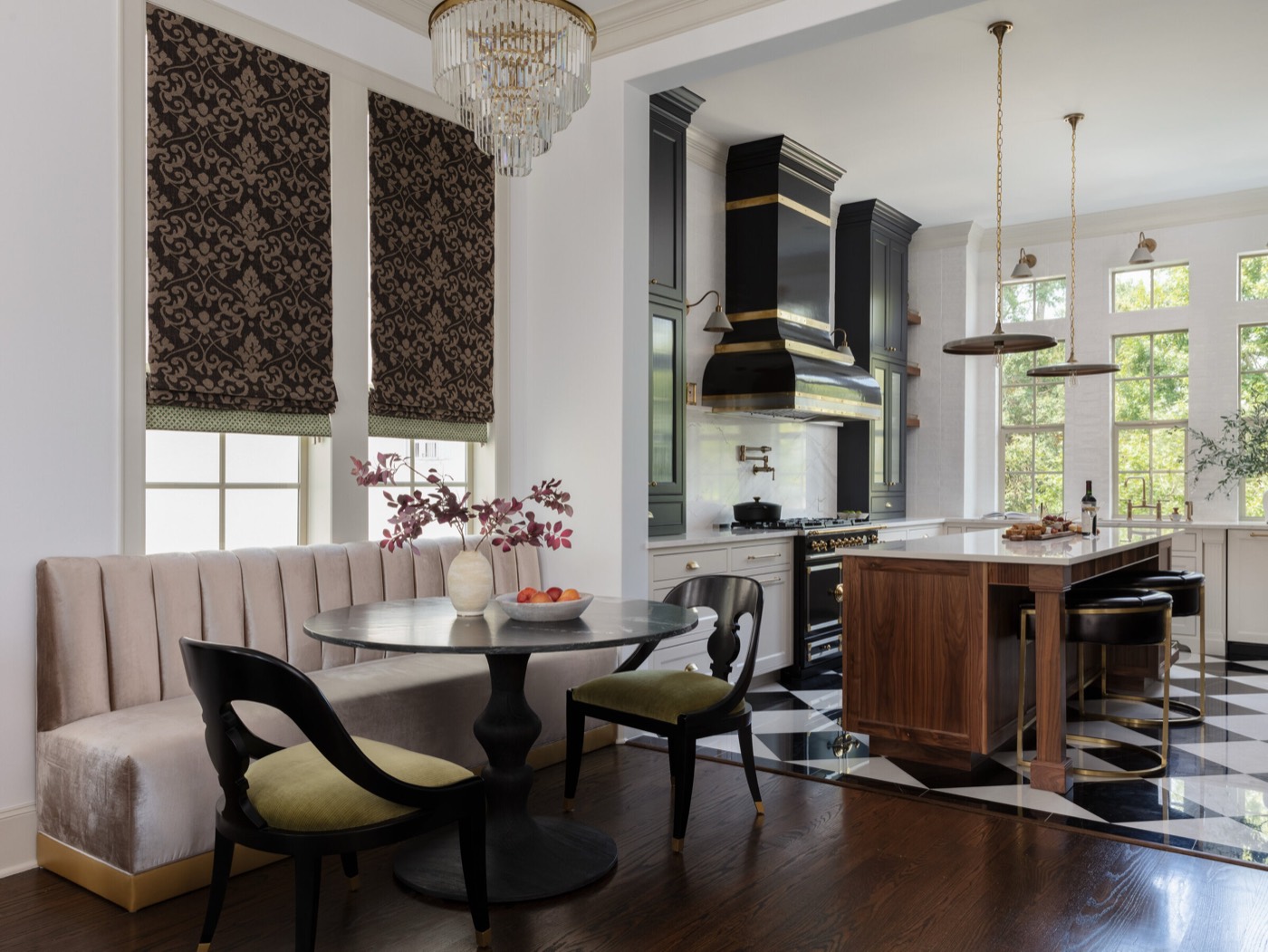 Kitchen and breakfast room with a channel-tufted banquette, crystal chandelier, and a walnut island on a black and white checkerboard marble floor in the Gateway Condo project by Jennifer Kizzee Design