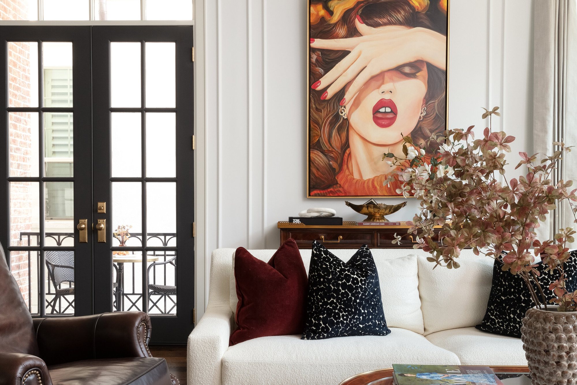 Living room with a large portrait canvas above a white sofa and a leather wing chair in the Gateway Condo project by Jennifer Kizzee Design