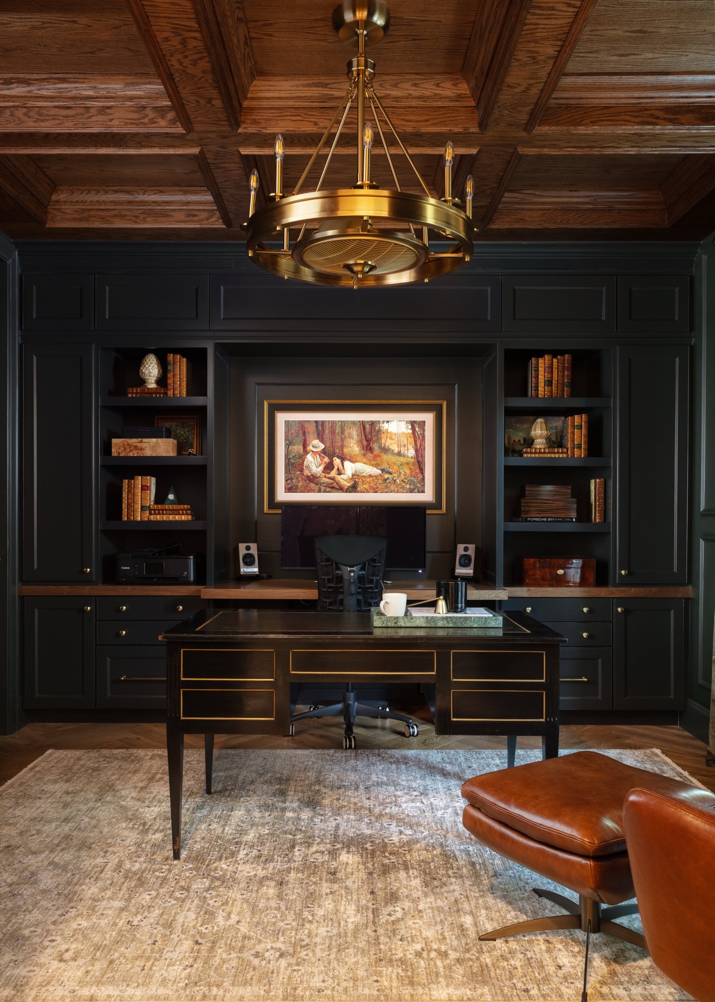 Study with near-black paneled built-ins beneath a stained oak coffered ceiling and a brass drum chandelier in the Gateway Condo project by Jennifer Kizzee Design