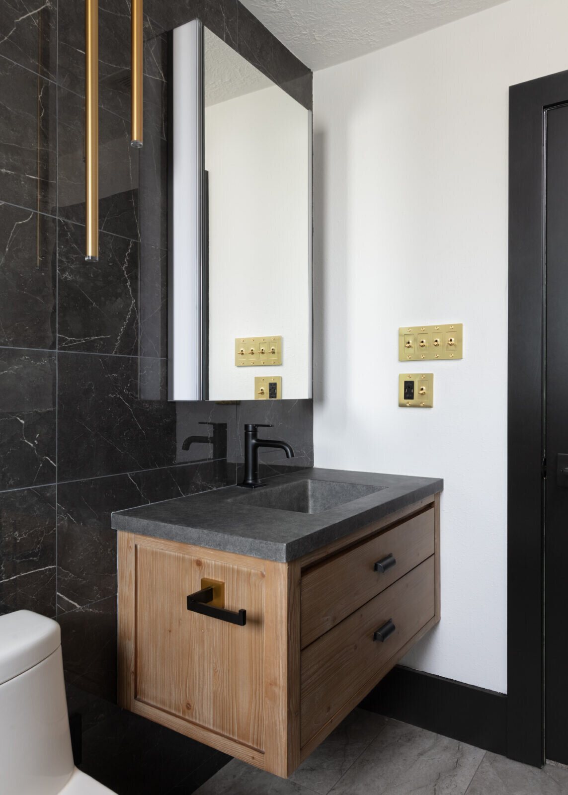Cedar vanity with black hardware and a rectangular mirror on black marble in the Gentleman's Retreat project by Jennifer Kizzee Design
