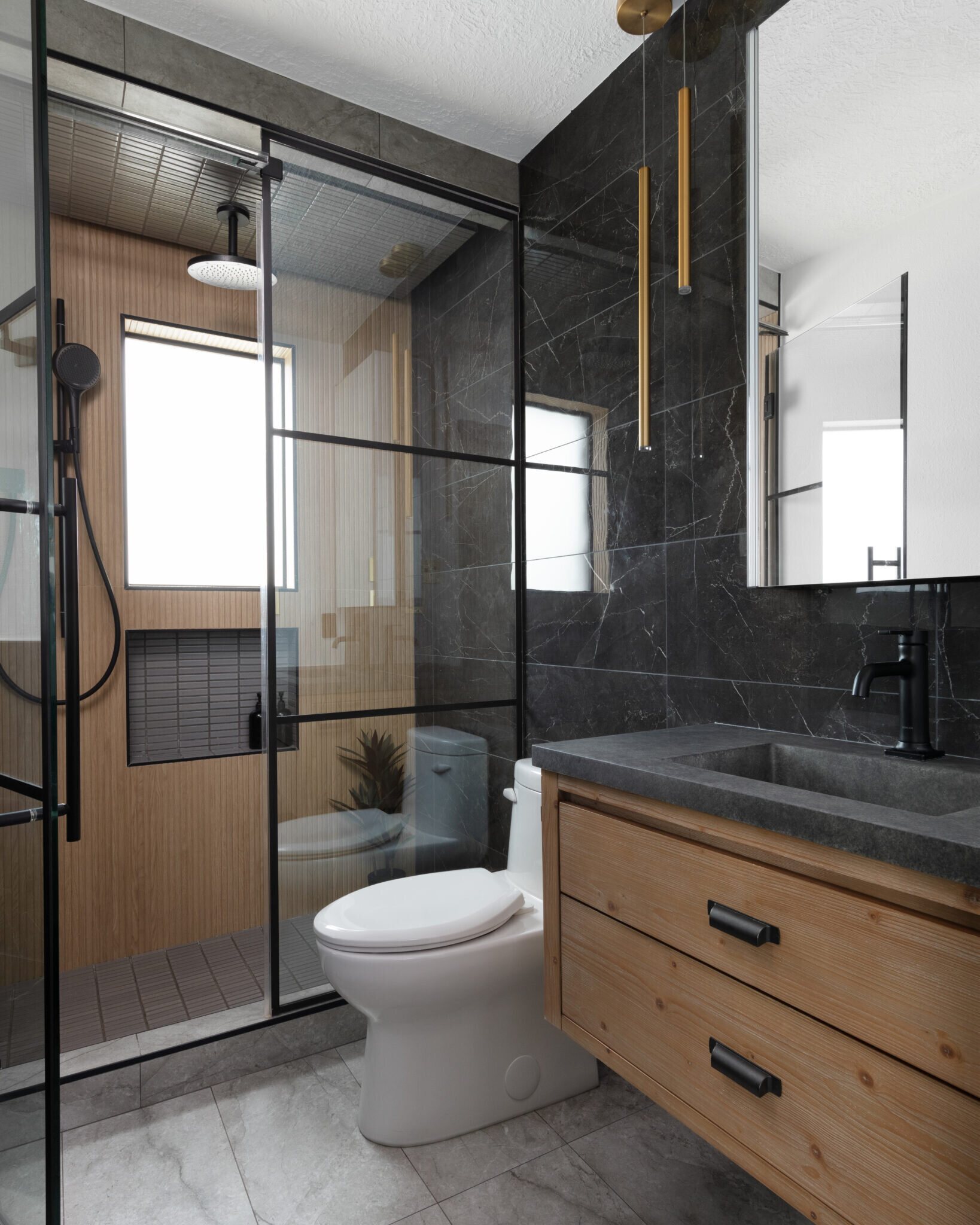 Dark bath with black marble walls, a floating cedar vanity and a slatted wood shower in the Gentleman's Retreat project by Jennifer Kizzee Design