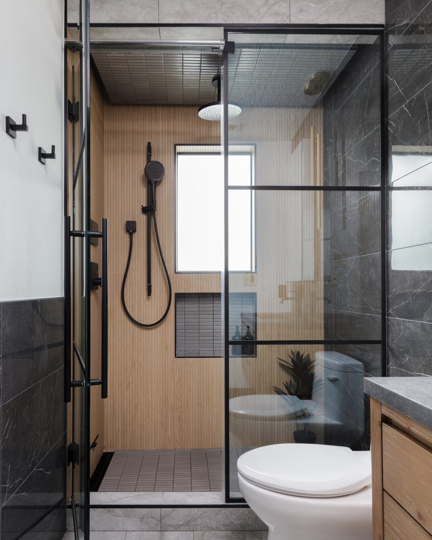 Shower lined in slatted wood behind black framed glass in the Gentleman's Retreat project by Jennifer Kizzee Design