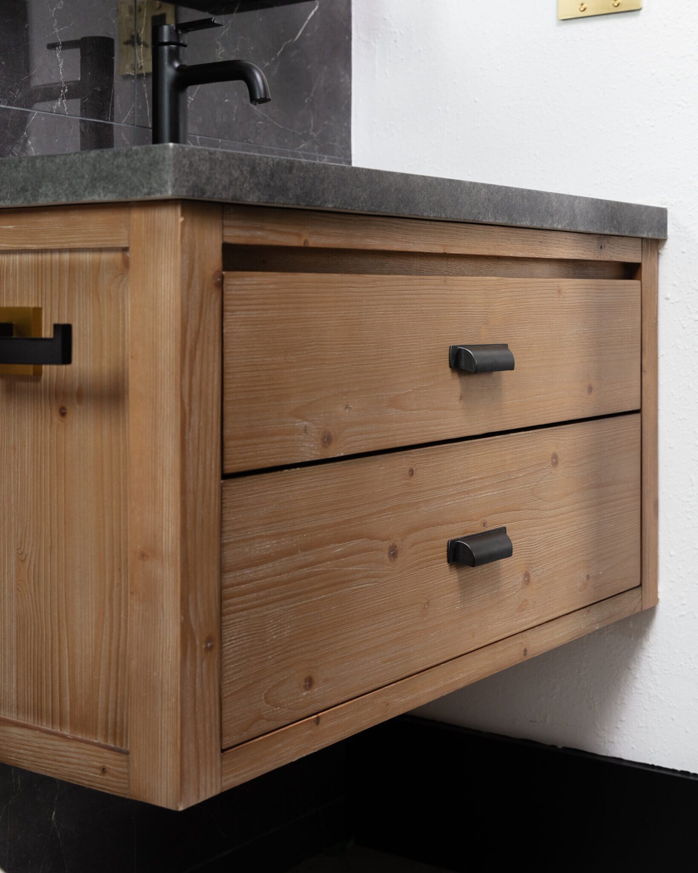 Stone basin set into the cedar vanity with a black faucet in the Gentleman's Retreat project by Jennifer Kizzee Design