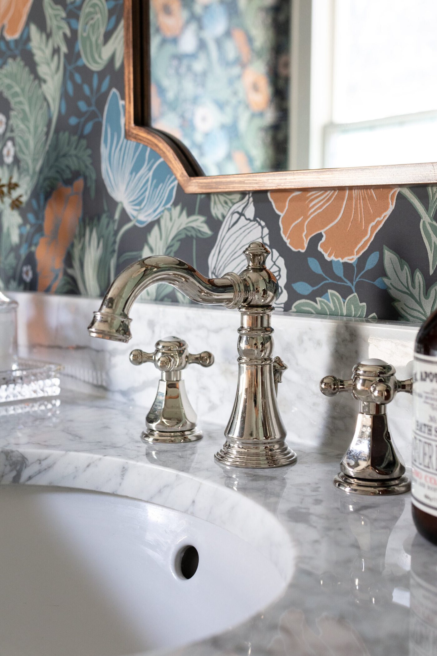 Polished nickel cross handle faucet on a marble counter under a gilt mirror in the Heights Primary Bath project by Jennifer Kizzee Design