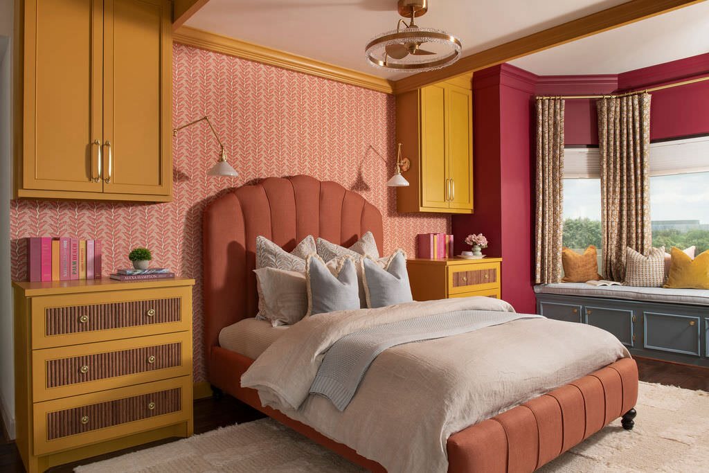 Bedroom with a terracotta channel tufted bed, mustard built-ins and pink patterned wallpaper in the Holcombe Condo project by Jennifer Kizzee Design