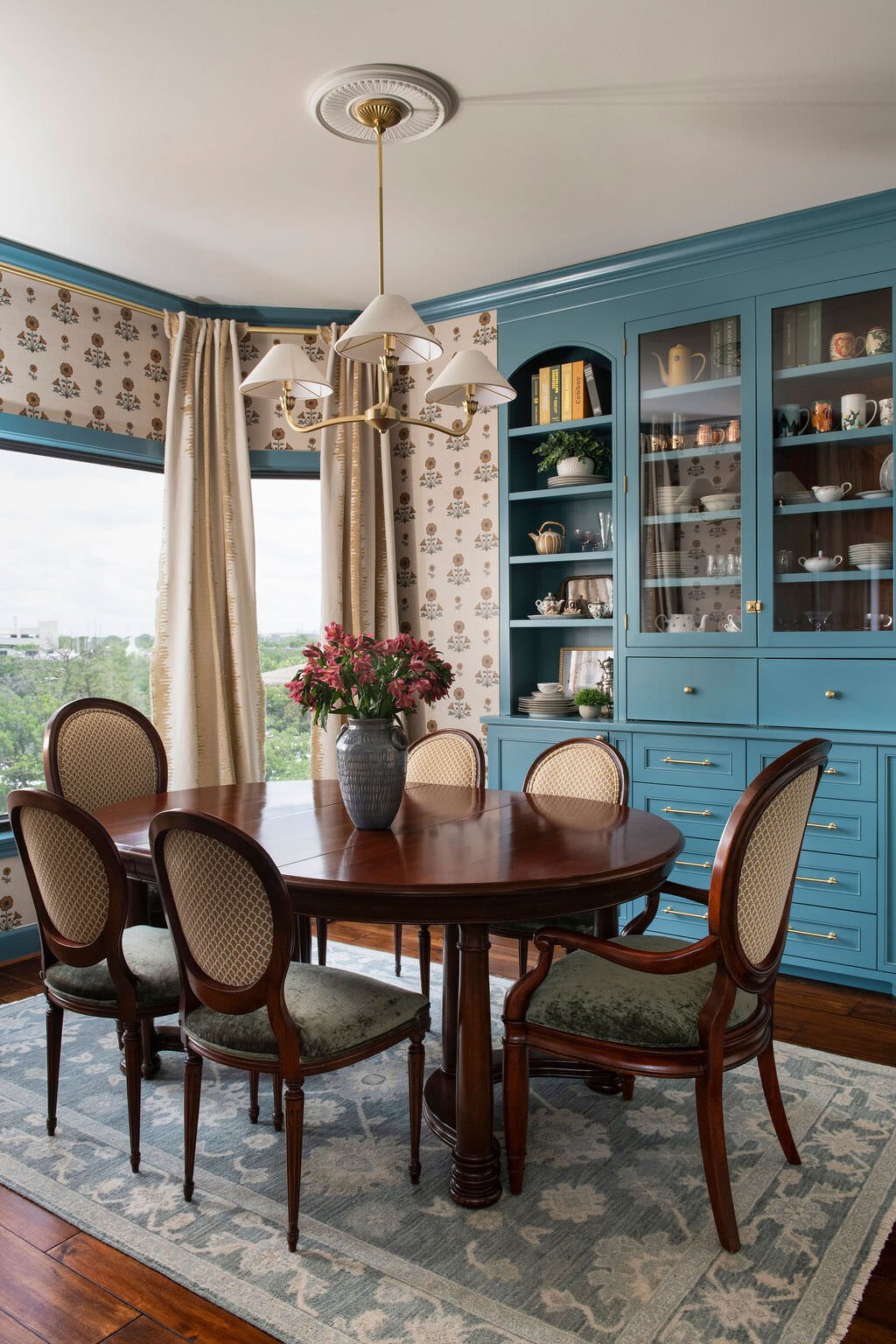 Round dining table with antique chairs in front of blue cabinetry in the Holcombe Condo project by Jennifer Kizzee Design