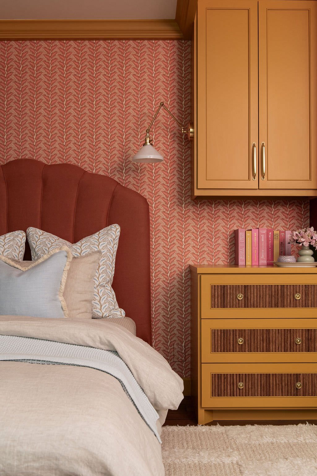 Terracotta channel tufted headboard beside a mustard chest with brass pulls in the Holcombe Condo project by Jennifer Kizzee Design