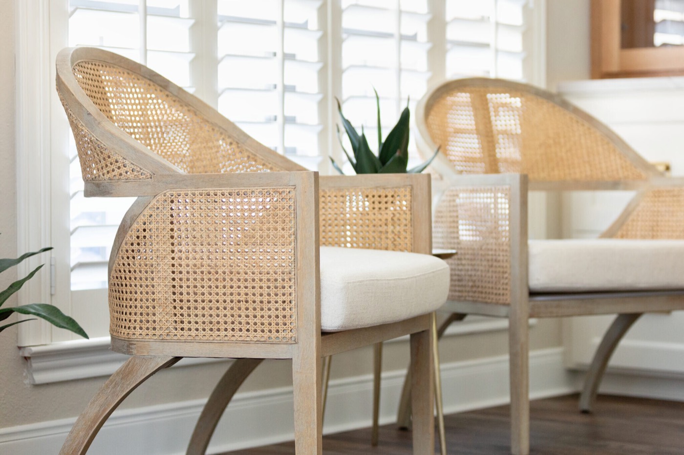 Cane barrel chairs in bleached wood against louvered plantation shutters in the Knoll Kitchen project by Jennifer Kizzee Design