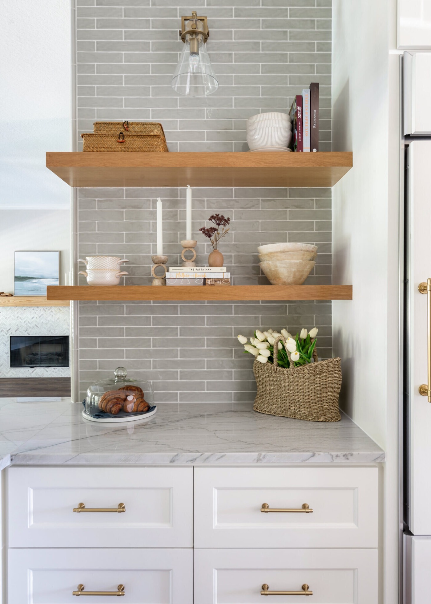 Coffee bar niche with white oak floating shelves over sage glazed brick tile and a brass and glass sconce in the Knoll Kitchen project by Jennifer Kizzee Design