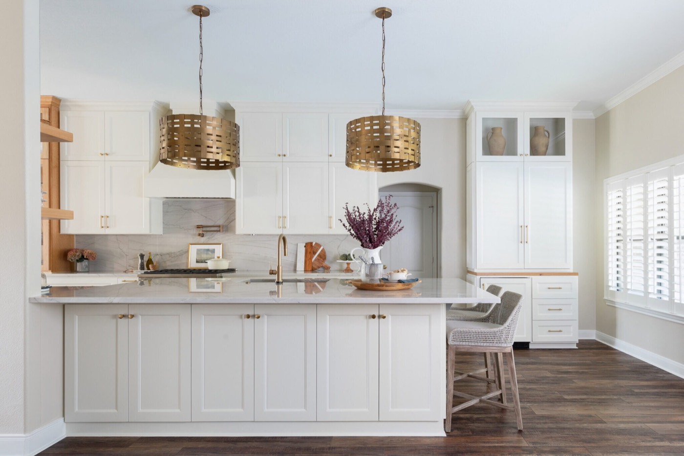 Kitchen island lit by brass drum pendants with cane barrel chairs in the Knoll Kitchen project by Jennifer Kizzee Design