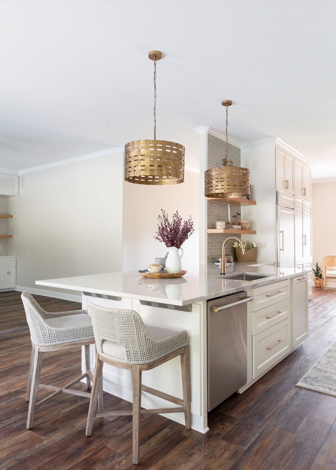 Kitchen island with brass gooseneck faucet and two woven counter stools under a pair of brass drum pendants in the Knoll Kitchen project by Jennifer Kizzee Design