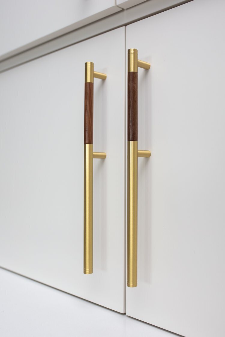Brass and walnut cabinet pulls on white doors in the Longwood project by Jennifer Kizzee Design