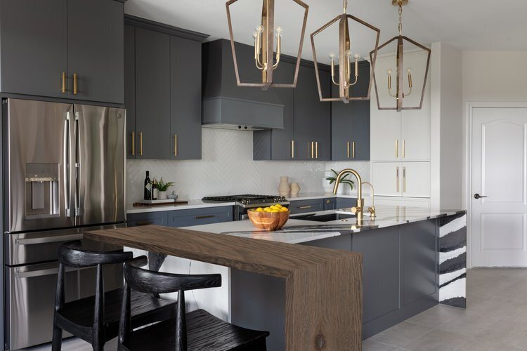 Charcoal island with black counter stools under brass lantern pendants in the Longwood project by Jennifer Kizzee Design