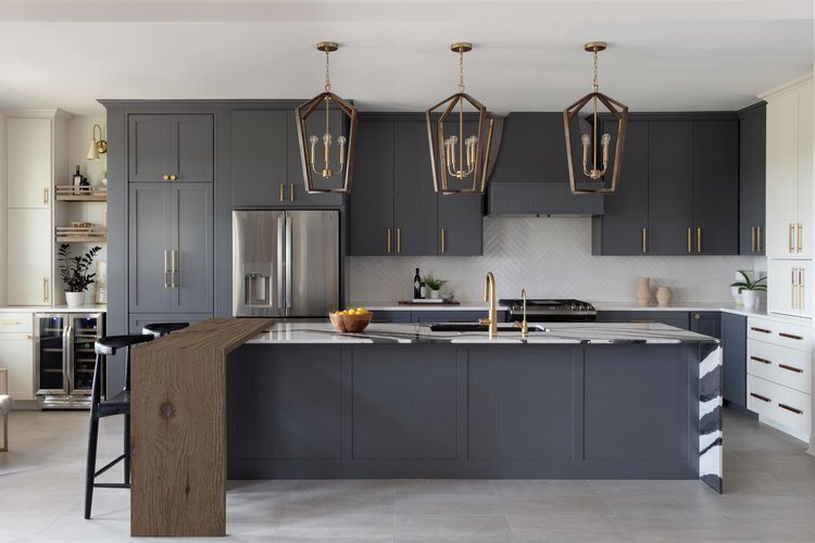 Charcoal kitchen with brass lantern pendants over an island edged in reclaimed wood in the Longwood project by Jennifer Kizzee Design