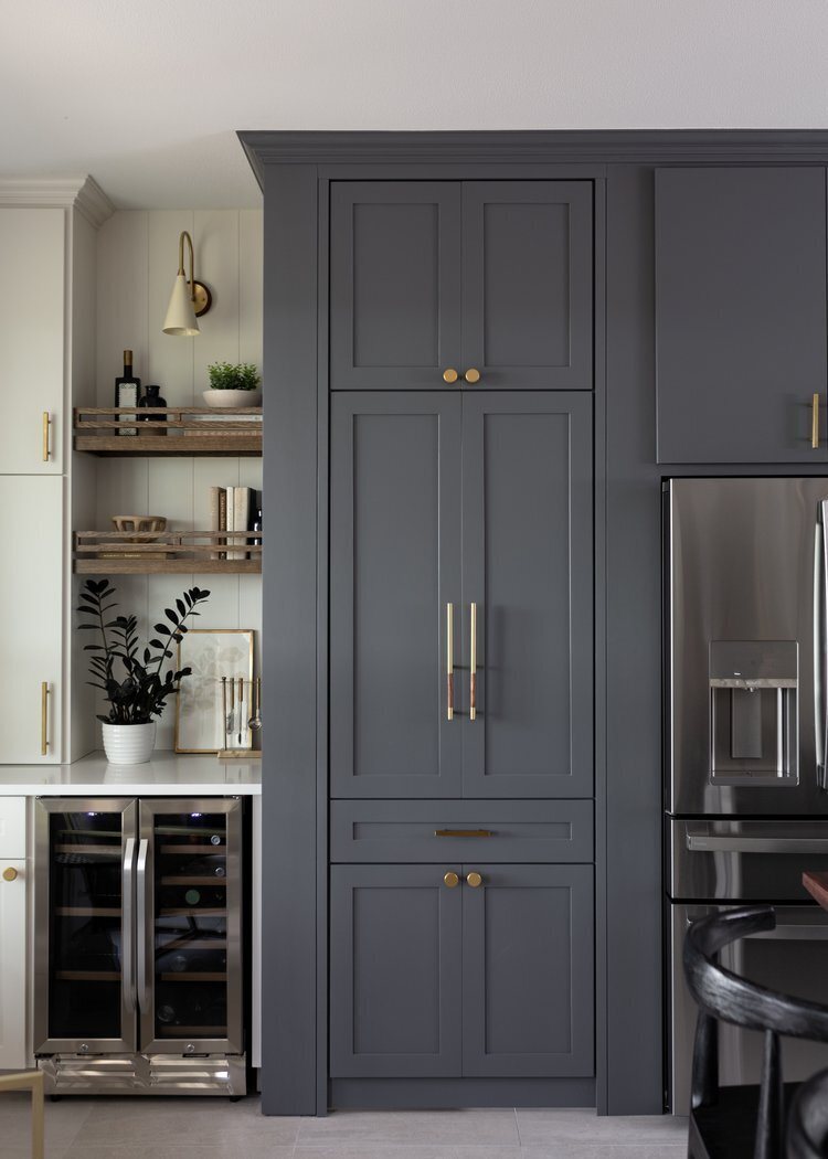 Charcoal pantry doors with brass pulls beside the refrigerator in the Longwood project by Jennifer Kizzee Design